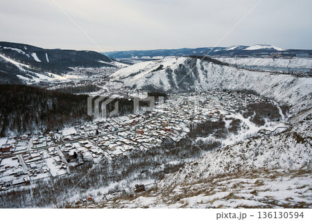 Aerial view of a snow covered village nestled in a valley with mountains and a river in winter. Landscape for travel, vacation spot. 136130594