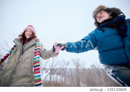 Couple walking in snowy forest holding hands and smiling. Couple walking in snowy forest holding hands and smiling. 136130600