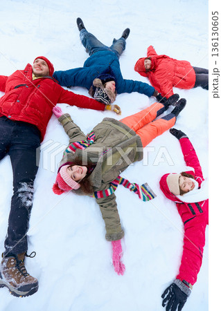 Group of friends lying in snow after winter sledding laughing together. Group of friends lying in snow after winter sledding laughing together. 136130605