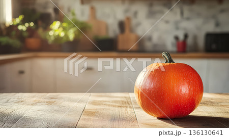 Large orange pumpkin sits on a wooden table in a kitchen 136130641