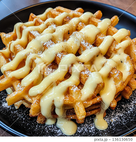 Plate of waffles covered in a creamy sauce and powdered sugar Plate of waffles covered in a creamy sauce and powdered sugar 136130650