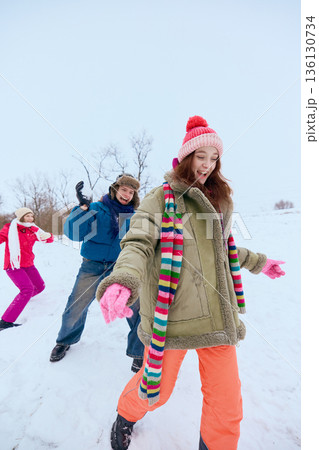 Friends laughing playing in snow during winter fun. Friends laughing playing in snow during winter fun. 136130734