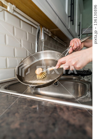 Woman washing dishes, frying pan with eco friendly wooden brush for sustainable lifestyle 136130896