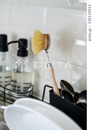 Wooden brush for washing dishes in the kitchen next to sink. Eco friendly, zero waste or conscious consumption concept. Copy space Wooden brush for washing dishes in the kitchen next to sink. Eco friendly, zero waste or conscious consumption concept. Copy space 136130915