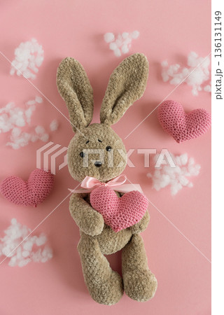 Plush Bunny with Knitted Hearts. Cute Valentines Day Flatlay on Pink Background Plush Bunny with Knitted Hearts. Cute Valentines Day Flatlay on Pink Background 136131149