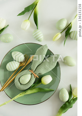 Easter Table Setting with Bunny Napkin, Decorated Eggs and Tulips. Festive Spring Flat Lay Easter Table Setting with Bunny Napkin, Decorated Eggs and Tulips. Festive Spring Flat Lay 136131158