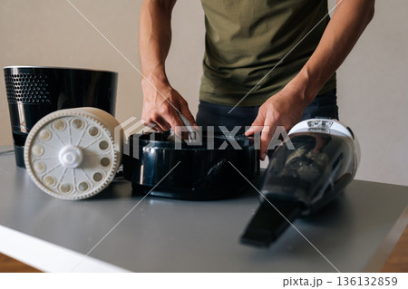 Cropped shot of technician male cleaning inside of air humidifier using cloth, with vacuum cleaner nearby to remove dust and debris, ensuring proper hygiene. Concept of cleanliness and housekeeping. 136132859