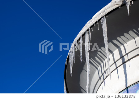 Frozen icicles under bright sky. Crisp shadows accentuate crystalline ice details Frozen icicles under bright sky. Crisp shadows accentuate crystalline ice details 136132878