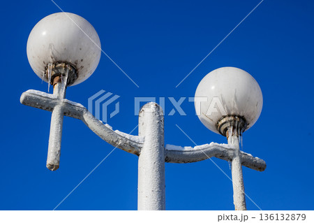 Closeup of spherical lamps with peeling paint against clear blue sky emphasizing form and texture 136132879