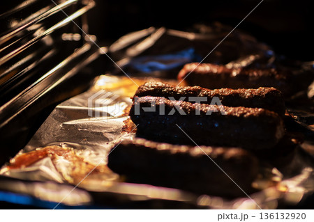 Closeup of sizzling sausages with crispy casings under gentle oven glow in kitchen Closeup of sizzling sausages with crispy casings under gentle oven glow in kitchen 136132920