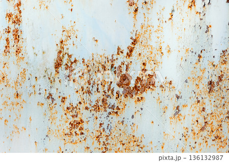 A close-up of a weathered metal panel showing orange rust specks and peeling paint 136132987