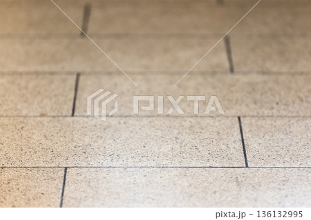 A close-up of a beige stone tile floor showing neat seams and fine grain 136132995
