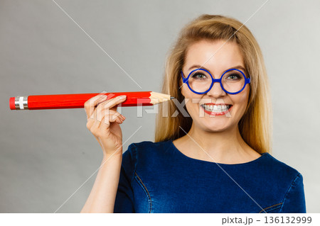 Smiling woman holds big pencil in hand Smiling woman holds big pencil in hand 136132999