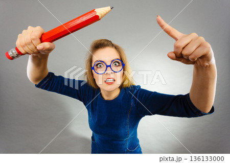 Angry woman holds big pencil in hand Angry woman holds big pencil in hand 136133000
