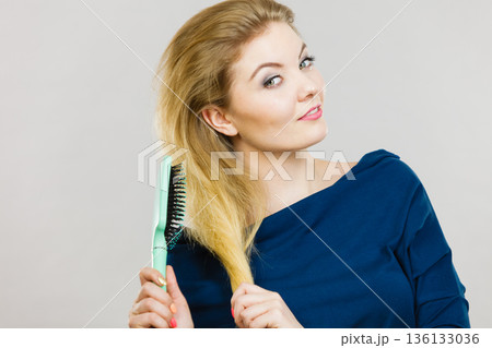 Woman brushing her long hair with brush 136133036