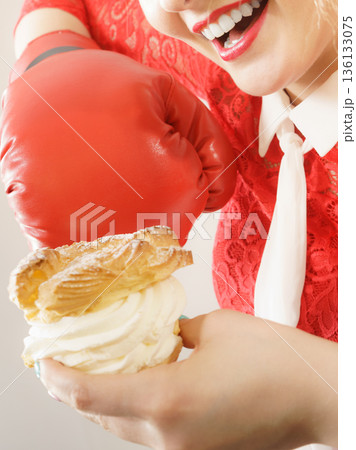 Woman fighting off bad food, boxing cream puff cake 136133075