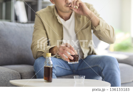 Man with alcohol addiction holding whiskey and cigarette at home, health risk 136133183