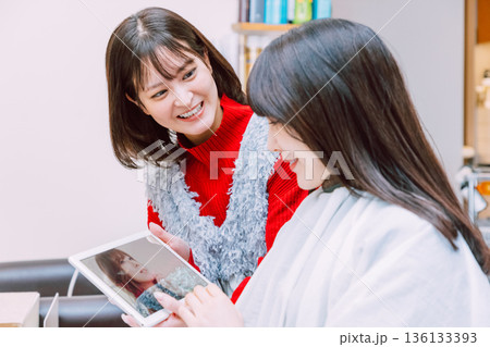 美容室で女性客にタブレットを見せる美容師 美容室で女性客にタブレットを見せる美容師 136133393