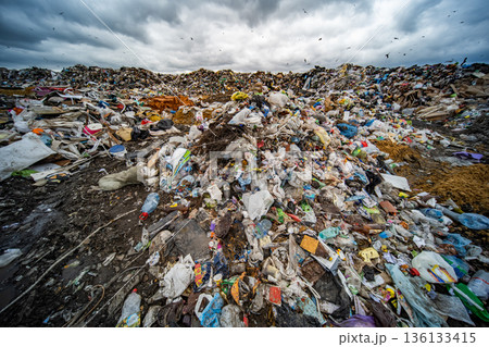 Overwhelming landfill showing massive waste piles under a dark, cloudy sky Overwhelming landfill showing massive waste piles under a dark, cloudy sky 136133415