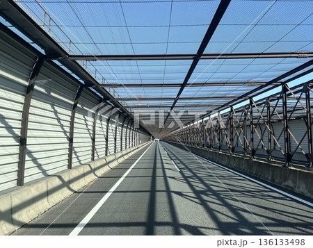 高速道路の防護ネット構造区間と光と影が伸びる直線道路風景 高速道路の防護ネット構造区間と光と影が伸びる直線道路風景 136133498