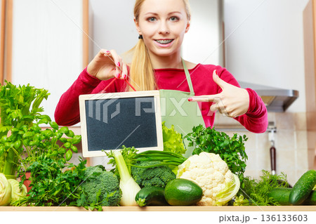 Woman having green vegetables holding board 136133603