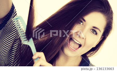 Woman brushing her long hair using comb 136133663
