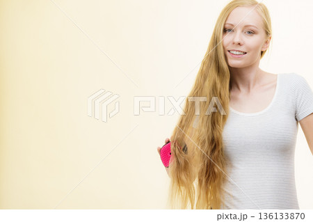 Blonde girl brushing her long hair 136133870