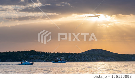 Sunset over the Adriatic sea and boat near the Sibenik city, Croatia. 136133898