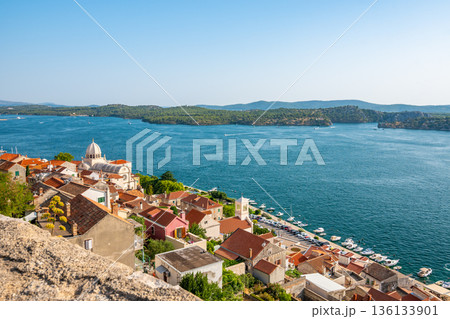 Coastal view of Sibenik old city, Croatia. Cathedral of St James, adriatic sea with island in background. Summer weather, aerial view of city roofs. UNESCO heritage. 136133901