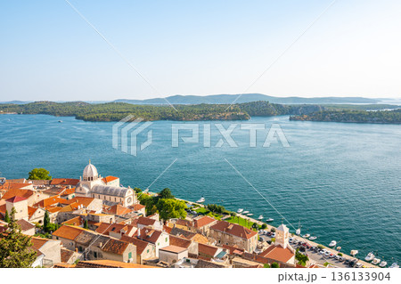 Coastal view of Sibenik old city, Croatia. Cathedral of St James, adriatic sea with island in background. Summer weather, aerial view of city roofs. UNESCO heritage. 136133904