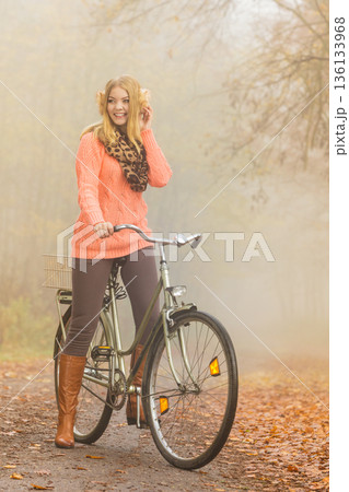 Happy active woman riding bike in autumn park. 136133968