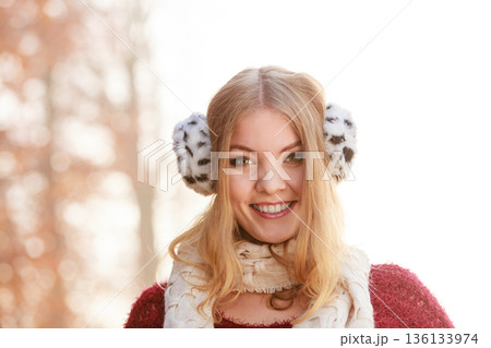 Portrait of pretty smiling woman in fur earmuffs. 136133974