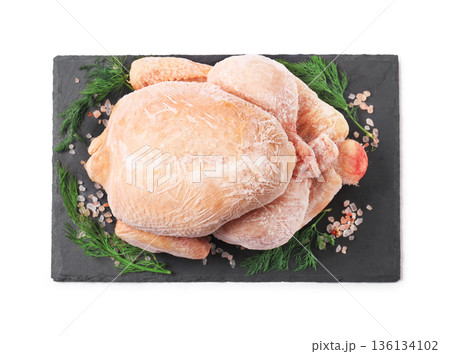 Whole frozen chicken on black slate board with dill and salt isolated on white background. Top view of raw poultry meat with ice crystals ready for cooking. High quality photo Whole frozen chicken on black slate board with dill and salt isolated on white background. Top view of raw poultry meat with ice crystals ready for cooking. High quality photo 136134102