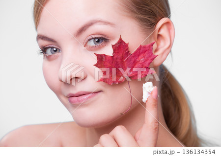 Skin care. Face of young woman girl with red maple leaf. Skin care. Face of young woman girl with red maple leaf. 136134354