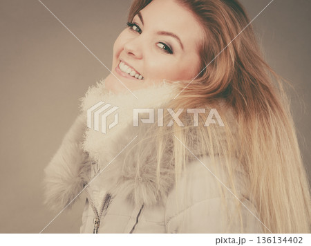 Happy woman wearing winter warm furry jacket 136134402