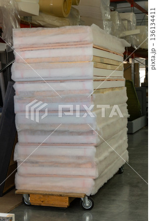 A stack of white fluffy polyester batting and foam is on a moving cart A stack of white fluffy polyester batting and foam is on a moving cart 136134411