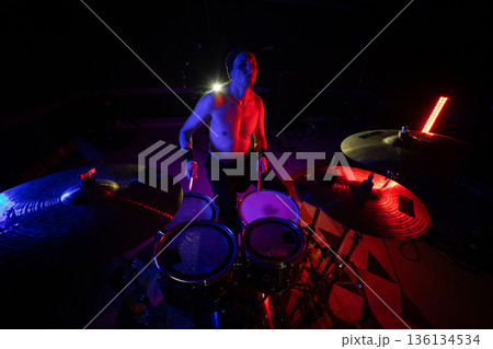 Musician playing drums on stage during a vibrant music show 136134534
