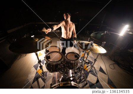 Male drummer playing drum kit in dark studio 136134535