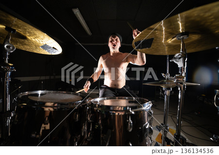 Male drummer playing drums with intense expression 136134536