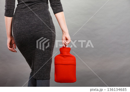 Woman holding warm red hot water bottle Woman holding warm red hot water bottle 136134685