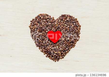buckwheat groats heart shaped on wooden surface. 136134696