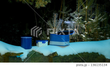 blue bag and containers on a snowy log at night 136135134
