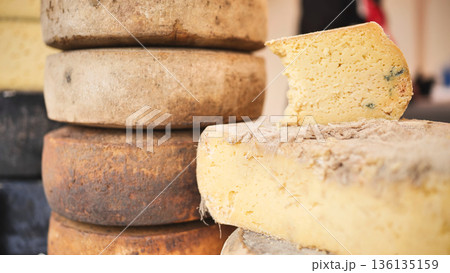 Artisan cheese wheels stacking, offering gourmet selection at market stall 136135159