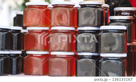 Glass jars filled with sweet honey stacked for sale Glass jars filled with sweet honey stacked for sale 136135167