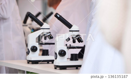 Students in lab coats using microscopes for science education Students in lab coats using microscopes for science education 136135187