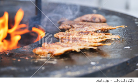 Fish grilling over fire on street food barbecue Fish grilling over fire on street food barbecue 136135229