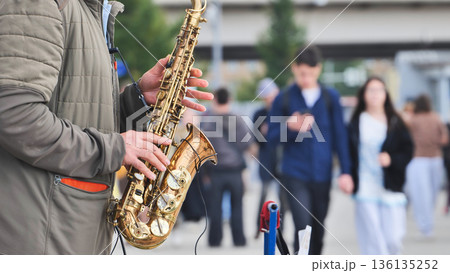 Saxophonist playing jazz music on a street performance in a busy city square 136135252