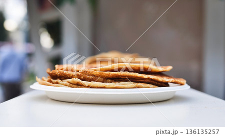 Stacked crepes steaming on a plate, representing fresh street food breakfast. 136135257