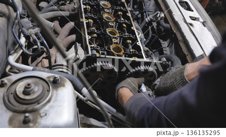 Mechanic working on car engine repair in a garage 136135295