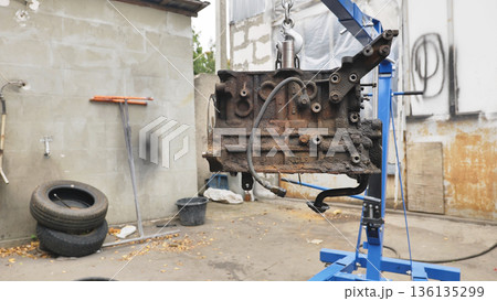 Car engine block on hoist in auto workshop 136135299